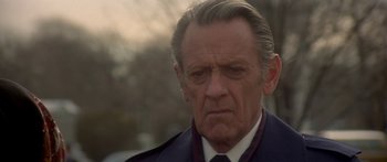 Movie still from “Damien: Omen II” (1978), directed by Mike Hodges – An older man with a serious look on his face; Close Up shot, Low angle