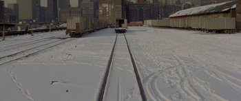 Movie still from “Damien: Omen II” (1978), directed by Mike Hodges – A train tracks covered in snow in a city; Extreme Wide shot, High angle