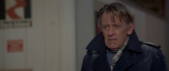 Movie still from “Damien: Omen II” (1978), directed by Mike Hodges – An older man wearing a jacket and a plaid scarf; Close Up shot, Over the shoulder angle