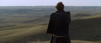 Movie still from “Dances with Wolves” (1990), directed by Kevin Costner – A man standing on top of a grass covered hill; Extreme Wide shot, Over the shoulder angle