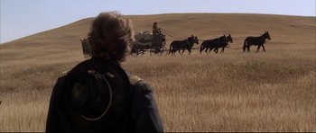 Movie still from “Dances with Wolves” (1990), directed by Kevin Costner – A man is standing in the middle of a field with horses; Wide shot, Over the shoulder angle