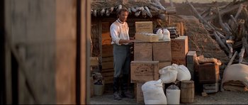 Movie still from “Dances with Wolves” (1990), directed by Kevin Costner – A man standing in front of boxes in a barn; Wide shot, Low angle