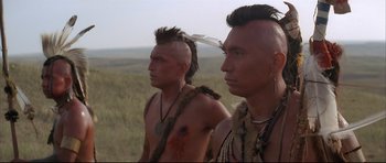 Movie still from “Dances with Wolves” (1990), directed by Kevin Costner – A couple of men standing on top of a grass covered field; Close Up shot, Over the shoulder angle