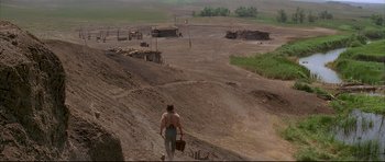 Movie still from “Dances with Wolves” (1990), directed by Kevin Costner – A man walking down a dirt road carrying a basket; Extreme Wide shot, High angle