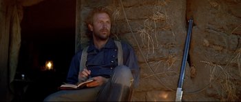 Movie still from “Dances with Wolves” (1990), directed by Kevin Costner – A man sitting on the ground reading a book; Close Up shot, Low angle