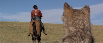 Movie still from “Dances with Wolves” (1990), directed by Kevin Costner – A man on a horse with a dog in the background; Wide shot, Over the shoulder angle