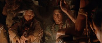 Movie still from “Dances with Wolves” (1990), directed by Kevin Costner – A man sitting next to another man on a couch; Medium shot, Over the shoulder angle