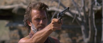 Movie still from “Dances with Wolves” (1990), directed by Kevin Costner – A man holding a gun in his right hand; Close Up shot, Low angle
