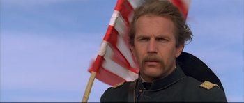 Movie still from “Dances with Wolves” (1990), directed by Kevin Costner – A person with a flag in the background; Close Up shot, Low angle
