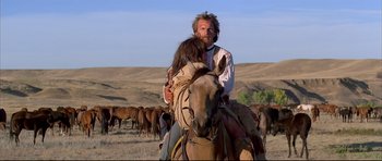 Movie still from “Dances with Wolves” (1990), directed by Kevin Costner – A man and a woman on a horse in a field; Wide shot, Low angle