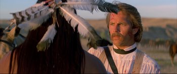 Movie still from “Dances with Wolves” (1990), directed by Kevin Costner – A man with a beard and a feather in his hand; Close Up shot, Over the shoulder angle