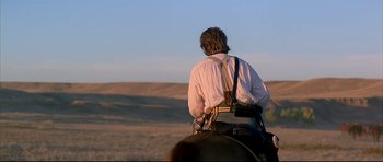Movie still from “Dances with Wolves” (1990), directed by Kevin Costner – A person riding a horse in a field; Wide shot, Over the shoulder angle