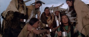 Movie still from “Dances with Wolves” (1990), directed by Kevin Costner – A group of native american men in traditional clothing holding cups; Medium shot, Low angle