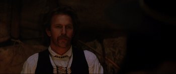 Movie still from “Dances with Wolves” (1990), directed by Kevin Costner – A man with a beard wearing a white shirt and a black vest; Close Up shot, Over the shoulder angle