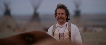 Movie still from “Dances with Wolves” (1990), directed by Kevin Costner – A man with long hair and a beard is smiling for the camera; Medium shot, Low angle