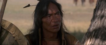 Movie still from “Dances with Wolves” (1990), directed by Kevin Costner – A man with long black hair wearing a brown jacket; Close Up shot, Over the shoulder angle