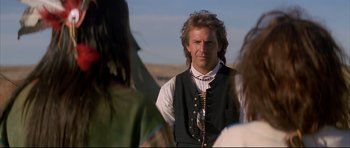 Movie still from “Dances with Wolves” (1990), directed by Kevin Costner – A man with long hair wearing a black vest; Close Up shot, Over the shoulder angle
