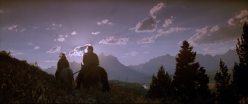 Movie still from “Dances with Wolves” (1990), directed by Kevin Costner – A man riding a horse in the mountains at dusk; Wide shot, Low angle