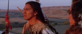 Movie still from “Dances with Wolves” (1990), directed by Kevin Costner – A man in a native american outfit with a feather in his head; Close Up shot, Low angle