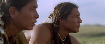 Movie still from “Dances with Wolves” (1990), directed by Kevin Costner – Two native american men standing next to each other; Close Up shot, Low angle