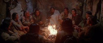 Movie still from “Dances with Wolves” (1990), directed by Kevin Costner – A group of people sitting around a fire pit; Wide shot, High angle
