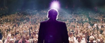 Movie still from “Danny Collins” (2015), directed by Dan Fogelman – A man standing in front of a crowd of people; Wide shot, Low angle