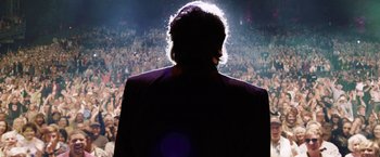 Movie still from “Danny Collins” (2015), directed by Dan Fogelman – A man standing in front of a crowd at a concert; Medium shot, Low angle