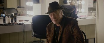 Movie still from “Danny Collins” (2015), directed by Dan Fogelman – An older man wearing a brown jacket and a brown hat; Close Up shot, Over the shoulder angle