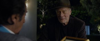 Movie still from “Danny Collins” (2015), directed by Dan Fogelman – An older man wearing a hat sitting at a table; Close Up shot, Over the shoulder angle
