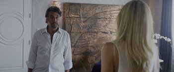 Movie still from “Danny Collins” (2015), directed by Dan Fogelman – A man standing next to a woman in front of a painting; Medium shot, Over the shoulder angle