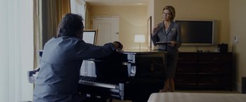 Movie still from “Danny Collins” (2015), directed by Dan Fogelman – Two people are standing in front of a black piano; Medium shot, Over the shoulder angle