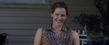 Movie still from “Danny Collins” (2015), directed by Dan Fogelman – A woman smiling for the camera in front of a house; Close Up shot, Over the shoulder angle