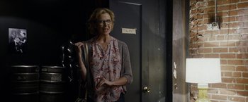 Movie still from “Danny Collins” (2015), directed by Dan Fogelman – A woman standing in front of a black door; Medium shot, Over the shoulder angle