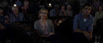 Movie still from “Danny Collins” (2015), directed by Dan Fogelman – A group of people sitting in a room watching a movie; Medium shot, Over the shoulder angle