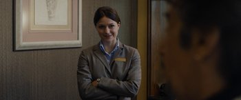 Movie still from “Danny Collins” (2015), directed by Dan Fogelman – A beautiful woman in a suit standing with her arms crossed; Close Up shot, Over the shoulder angle