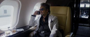 Movie still from “Danny Collins” (2015), directed by Dan Fogelman – A man sitting on a chair talking on a cell phone; Medium shot, Over the shoulder angle