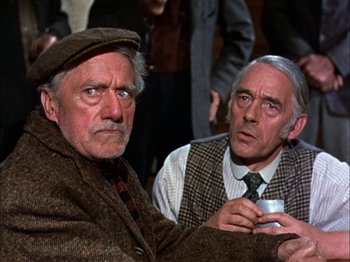 Movie still from “Darby O'Gill and the Little People” (1959), directed by Robert Stevenson – Two older men sitting next to each other holding a cup; Close Up shot, Over the shoulder angle