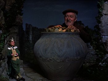 Movie still from “Darby O'Gill and the Little People” (1959), directed by Robert Stevenson – An old man is sitting in front of a giant pot of food; Medium shot, Low angle