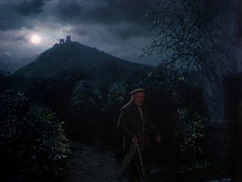 Movie still from “Darby O'Gill and the Little People” (1959), directed by Robert Stevenson – An old man with a cane walking down a path in the dark; Wide shot, Low angle