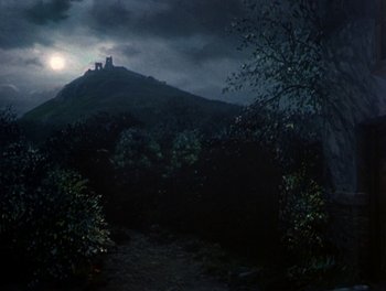 Movie still from “Darby O'Gill and the Little People” (1959), directed by Robert Stevenson – A view of a castle from the woods at night time; Extreme Wide shot, Low angle