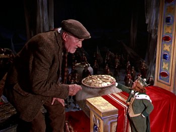 Movie still from “Darby O'Gill and the Little People” (1959), directed by Robert Stevenson – An old man holding a large pan in front of an elf; Wide shot, High angle