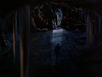Movie still from “Darby O'Gill and the Little People” (1959), directed by Robert Stevenson – A person is standing in a dark cave; Extreme Wide shot, High angle