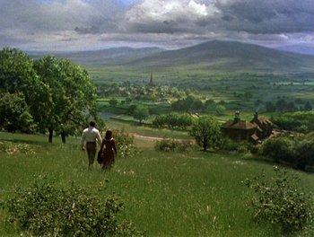 Movie still from “Darby O'Gill and the Little People” (1959), directed by Robert Stevenson – Two people walking in a field near a town; Extreme Wide shot, High angle