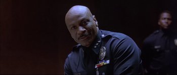 Movie still from “Dark Blue” (2002), directed by Ron Shelton – A man in a police uniform is smiling for the camera; Close Up shot, Low angle