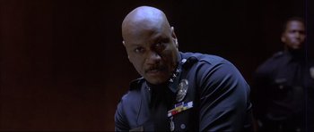 Movie still from “Dark Blue” (2002), directed by Ron Shelton – A man in a police uniform with a police badge on his chest; Close Up shot, Low angle