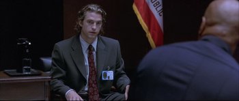Movie still from “Dark Blue” (2002), directed by Ron Shelton – A man in a suit sitting in front of an american flag; Medium shot, Over the shoulder angle