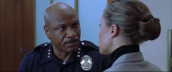 Movie still from “Dark Blue” (2002), directed by Ron Shelton – A police officer talking to a woman in a room; Close Up shot, Over the shoulder angle