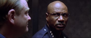 Movie still from “Dark Blue” (2002), directed by Ron Shelton – A man in a police uniform talking to another man; Close Up shot, Low angle