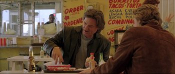 Movie still from “Dark Blue” (2002), directed by Ron Shelton – A man sitting at a table in front of food; Medium shot, Over the shoulder angle