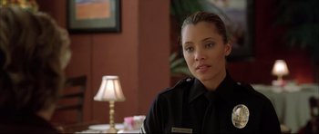 Movie still from “Dark Blue” (2002), directed by Ron Shelton – A woman in a uniform sitting in front of a lamp; Close Up shot, Over the shoulder angle